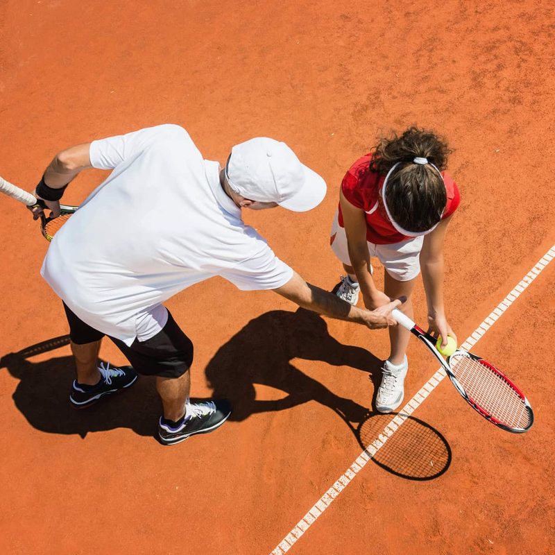 Maestro di tennis durante una lezione a bordo campo